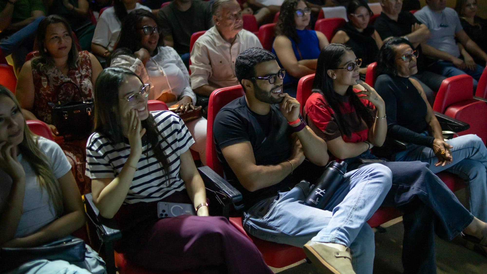 Fileira de espectadores rindo e prestando atenção no show